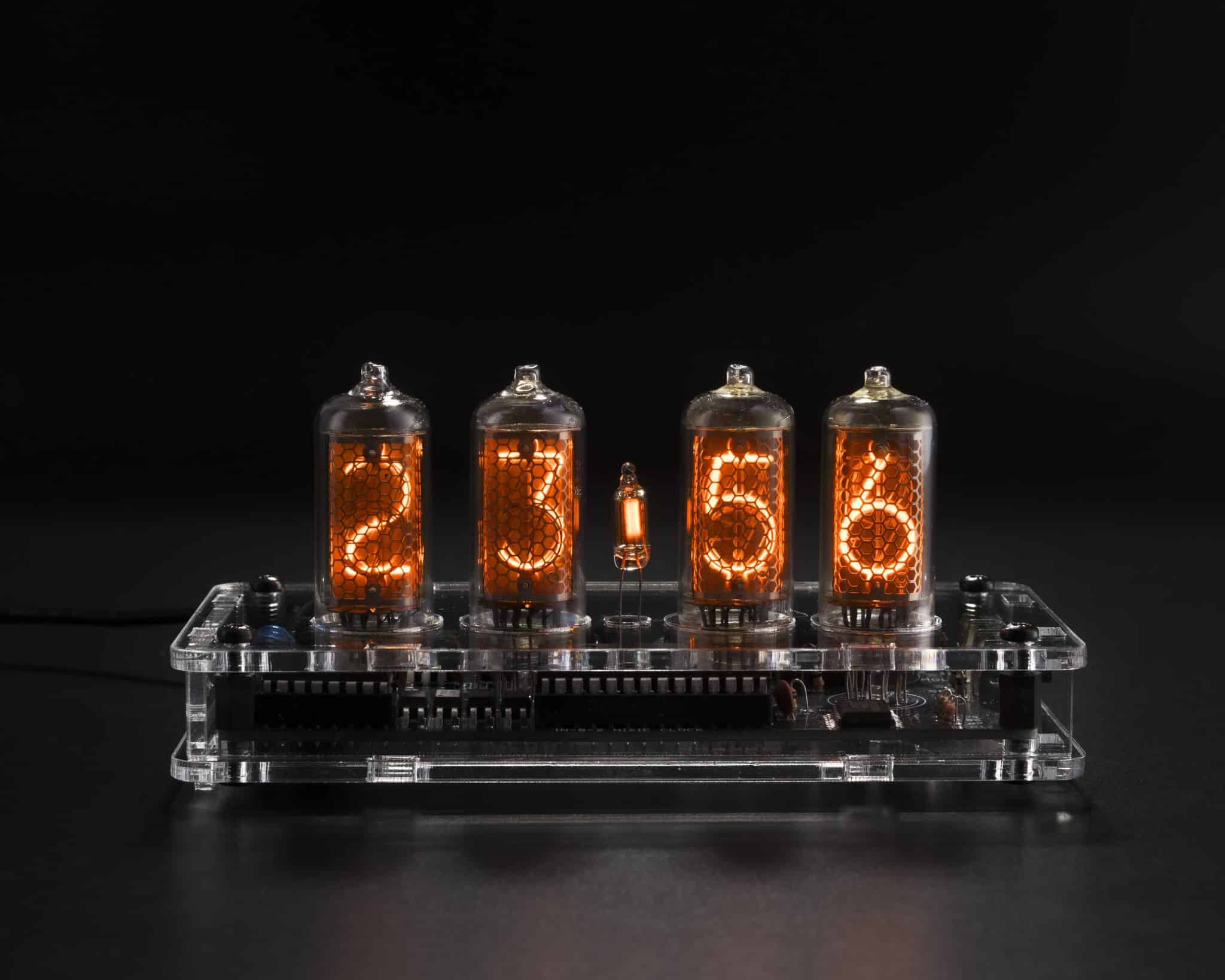 Front view of a four-tube IN-8-2 Nixie clock in a transparent acrylic case with the circuit board visible.