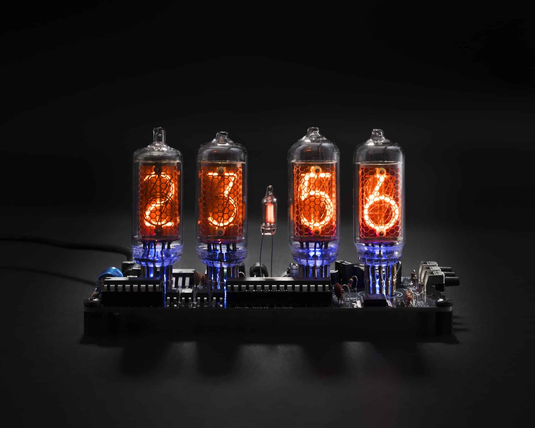 Front view of four glowing IN-8 Nixie tubes with blue backlighting on an exposed clock board.