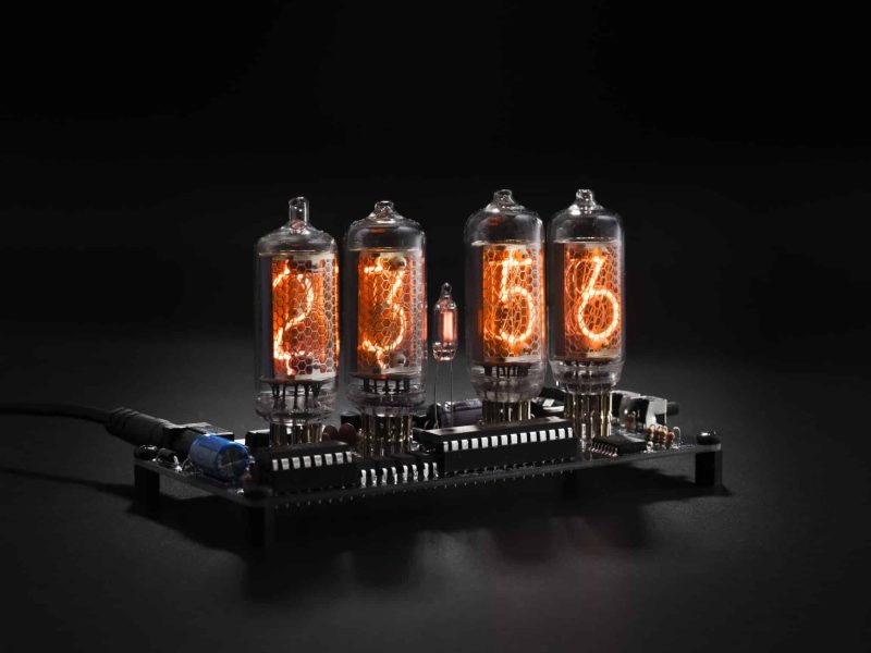 Angled view of four glowing IN-8 Nixie tubes on an exposed clock circuit board.