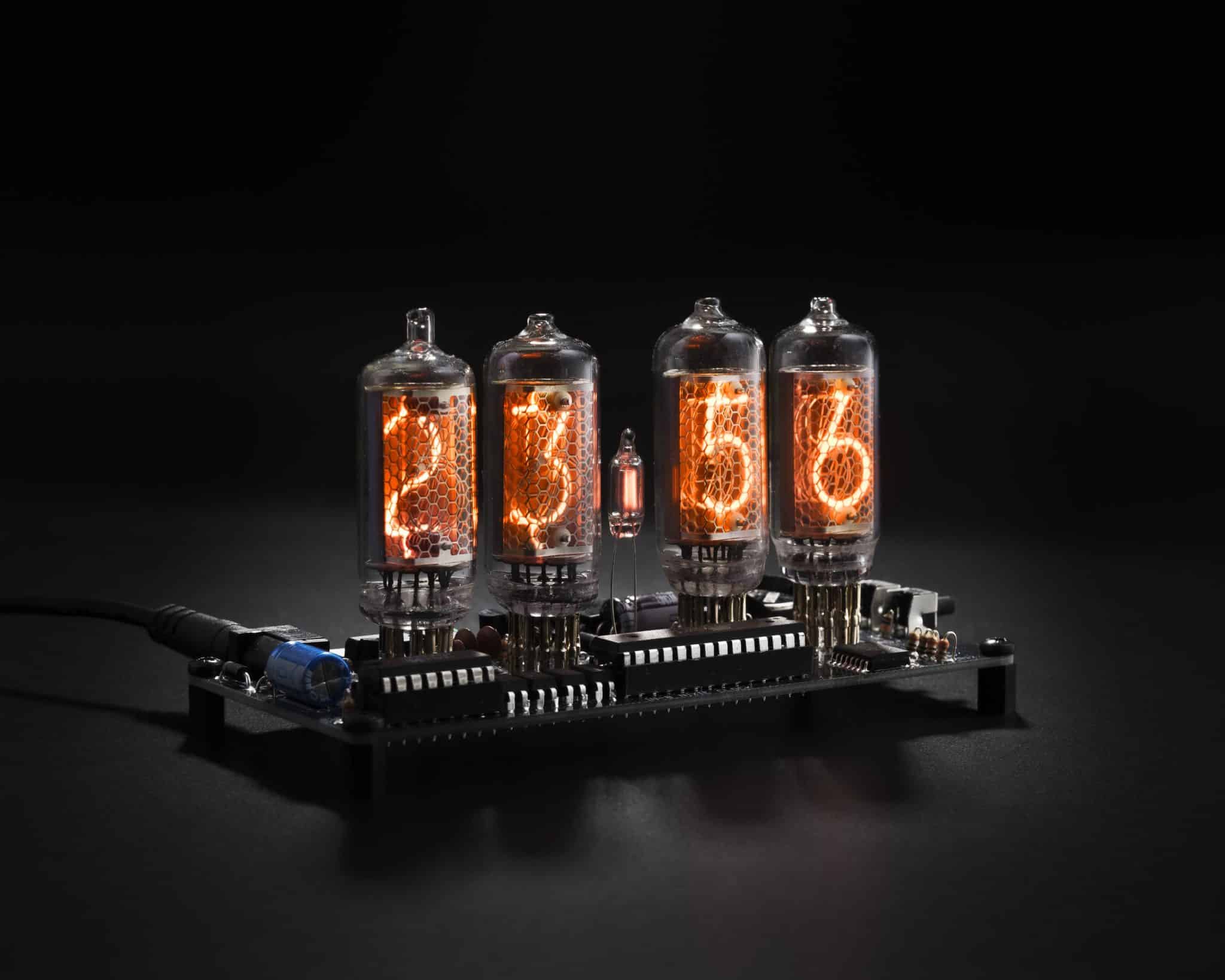 Angled view of four glowing IN-8 Nixie tubes on an exposed clock circuit board.