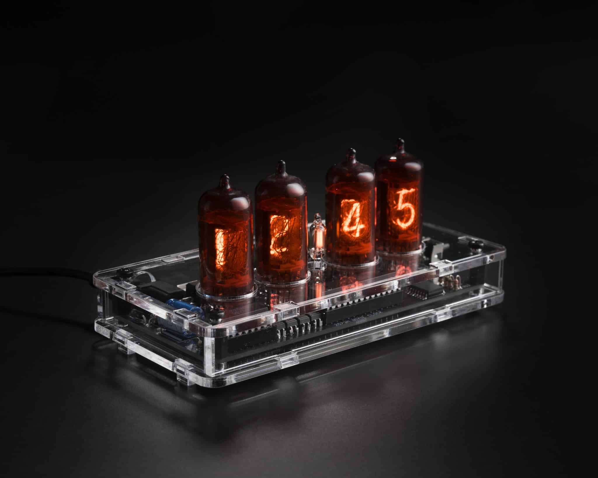 Four red-coated Z573M Nixie tubes in a transparent acrylic clock case, viewed at an angle.